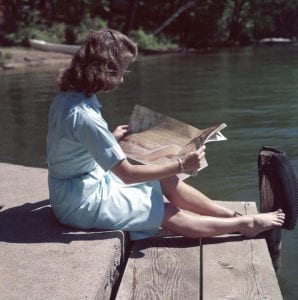 Woman reading magazine on dock
